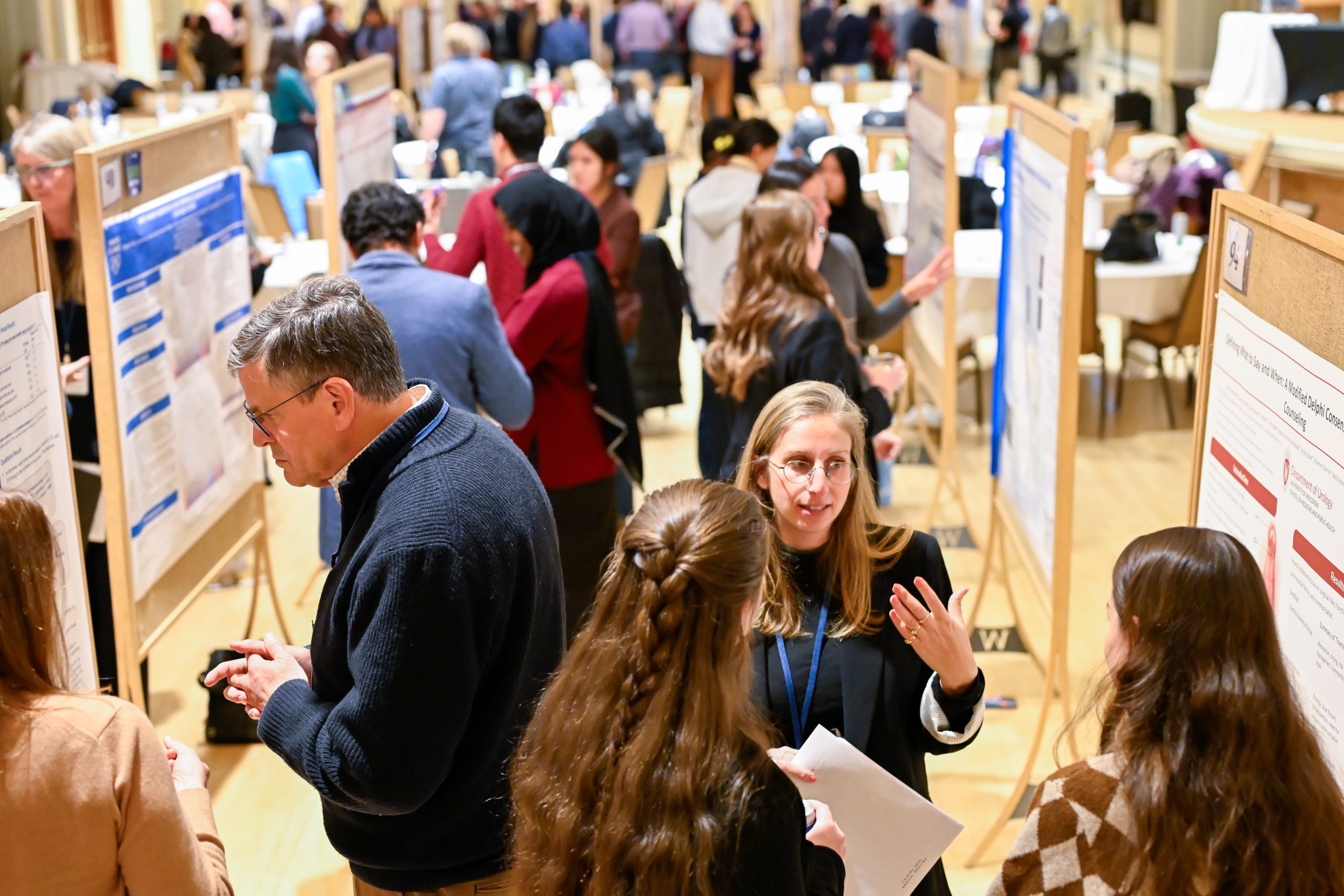 Picture of attendees reading posters and listening to poster presentations.